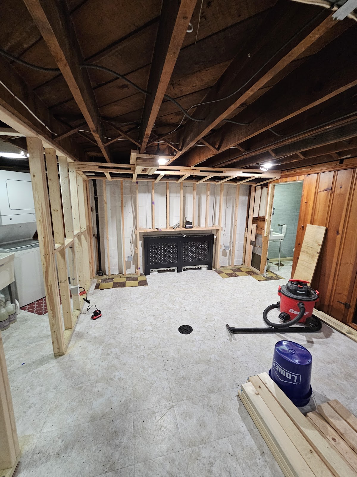 Basement remodel in progress with new framing, a built-in radiator cover, and waterproof flooring