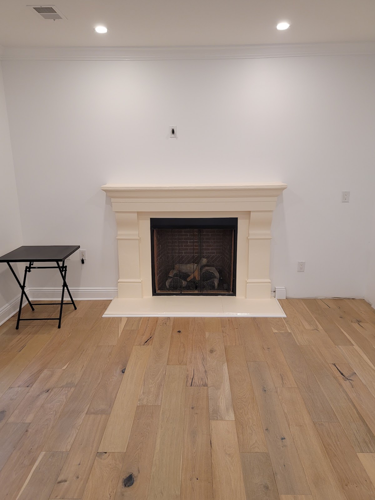 Finished living room with a new hardwood floor and painted fireplace surround